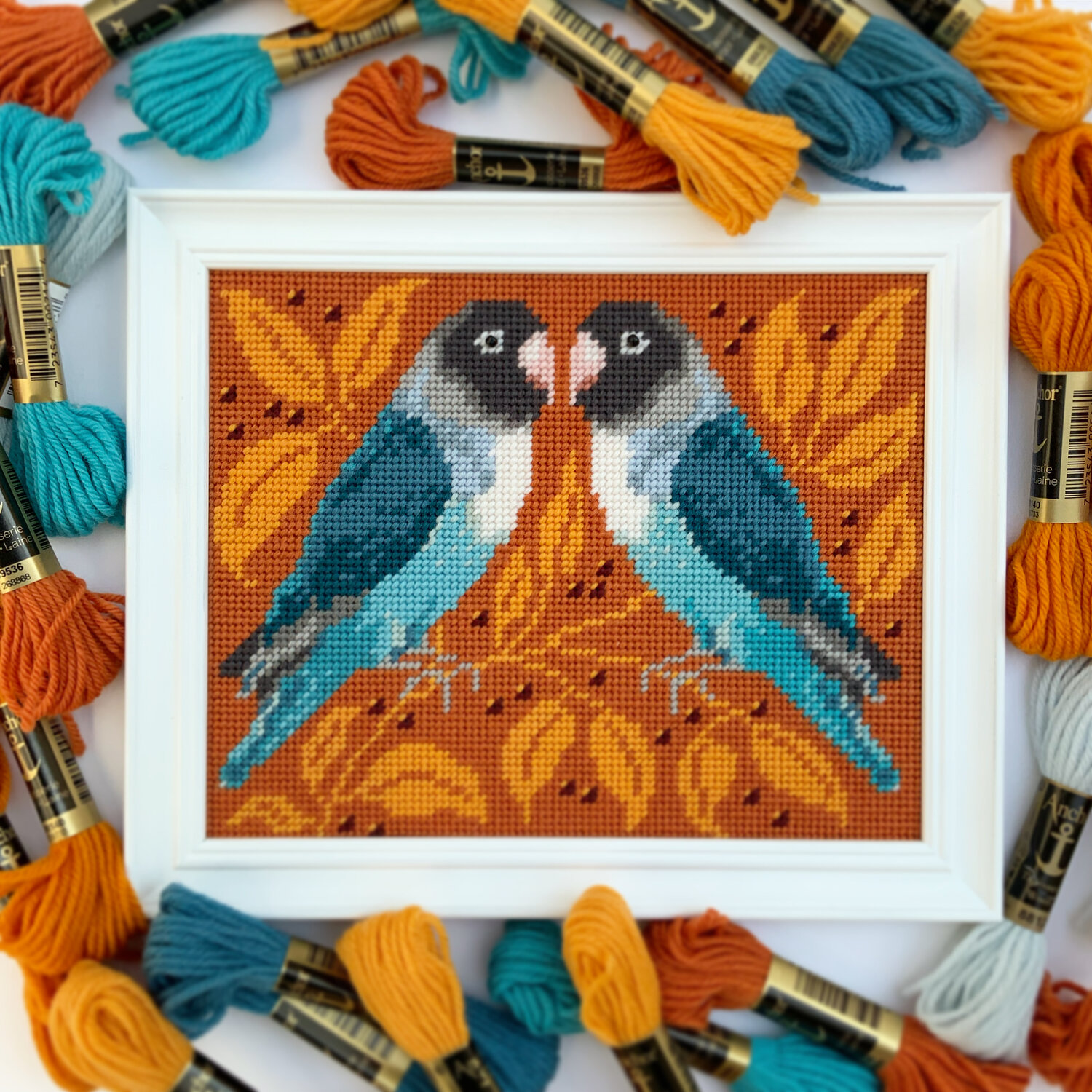 Needlepoint kit of two blue coloured love birds with an orange branch background. Designed by Ann's Orchard.