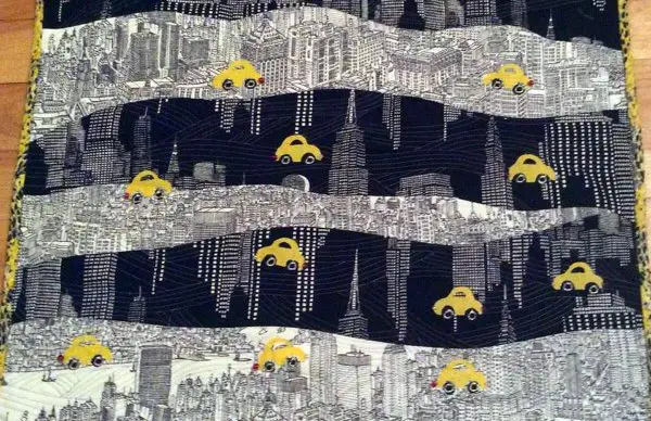 quilt art by Marijke Vroomen Druning with New York skyline scene in black and white with taxi print in yellow.