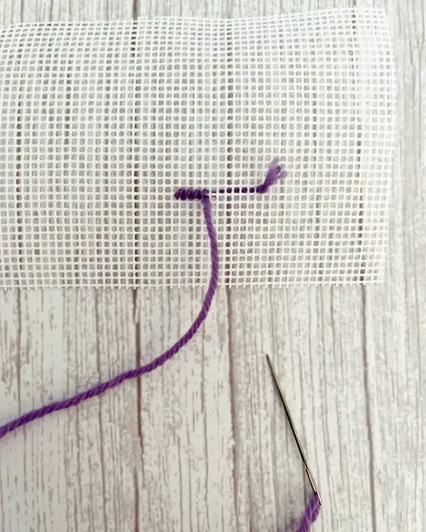 The waste knot method of casting on your thread is shown on needlepoint canvas.